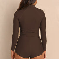 Woman wearing brown Aire Turtle Neck a high neck, minimalist long sleeve women’s rashguard made from sustainable fabric, designed for sun protection and surf performance.