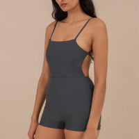 Model wearing blueish grey Terrain One Piece shorty surf suit — sustainable swimwear designed for support and comfort in the surf, flattering one piece surf suit for active women.