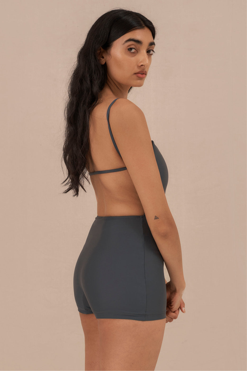 Model wearing blueish grey Terrain One Piece surf suit — sustainable swimwear designed for support and comfort in the surf, flattering one piece surf suit for active women.