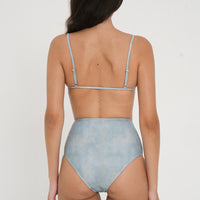 woman wearing fixed triangle bikini top in sea glass print, designed for both style and comfort. Crafted from 78% recycled nylon and 22% Lycra, offering a supportive and quick-drying fabric. Worn with matching high waisted sustainable swimwear bottoms.