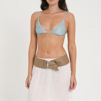 woman wearing fixed triangle bikini top in sea glass print, with minimalist leather belt and white skirt.