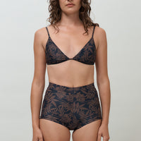A woman wearing a black and brown leaf print triangle bikini top with adjustable straps and removable cups.
