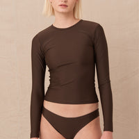 woman wearing brownlong sleeve minimalist rashguard sustainably made for sun protection and surfing.
