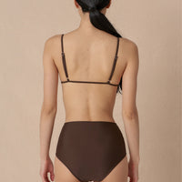 Woman wearing a brown minimalist triangle bikini top with adjustable straps and removable cups, paired with matching bottoms made with sustainable swimwear fabrics.