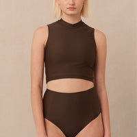 A high-waisted brown sustainable swimwear bikini bottom with minimalist design and moderate coverage, modelled by a woman in a matching bikini top.