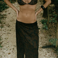 A woman wearing a leaf print triangle bikini top with matching sarong at the beach.