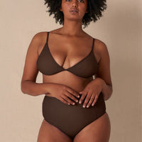 A high-waisted brown sustainable swimwear bikini bottom with minimalist design and moderate coverage, modelled by a woman in a matching bikini top.